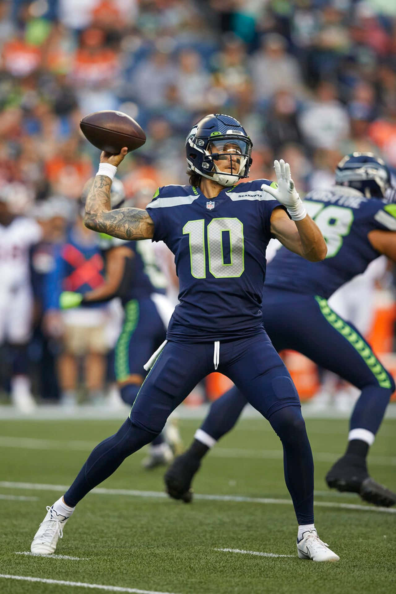 Usfl 桌布 壁紙 — 西雅圖海鷹隊的四分衛身穿海軍藍球衣，背號10，在白天比賽中準備擲出橄欖球，背景是模糊的體育場人群。