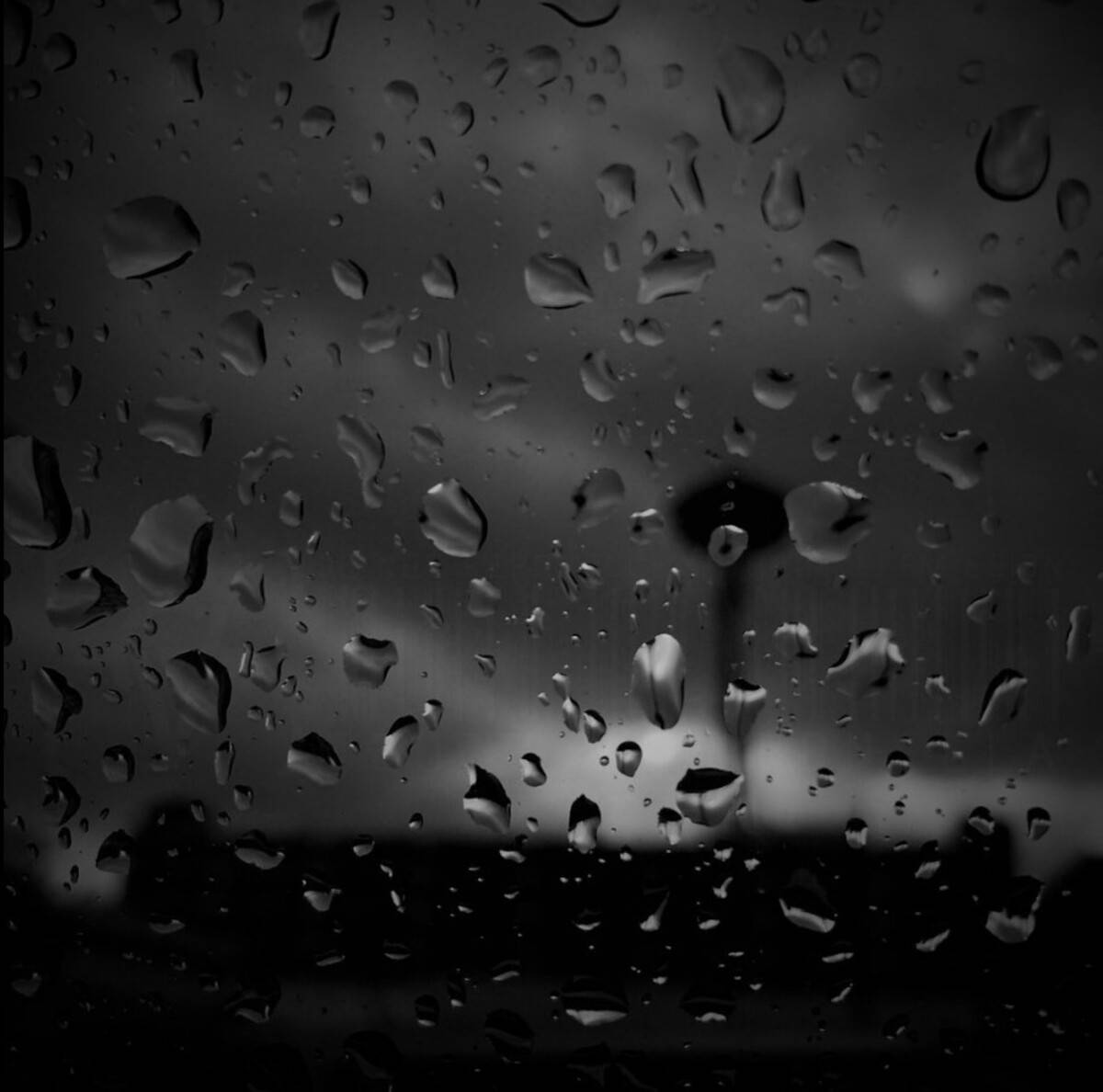 車窗上的雨滴，遠處模糊的城市塔樓。