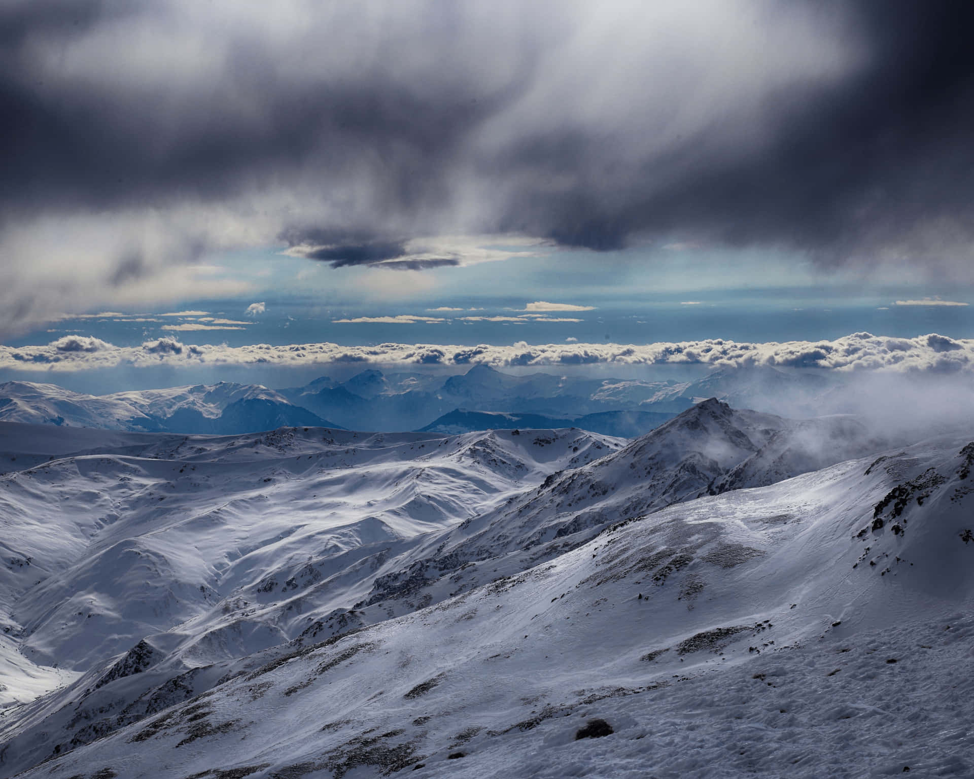 暴風雨天空下，陽光穿透雲層照耀的雪山山脈。