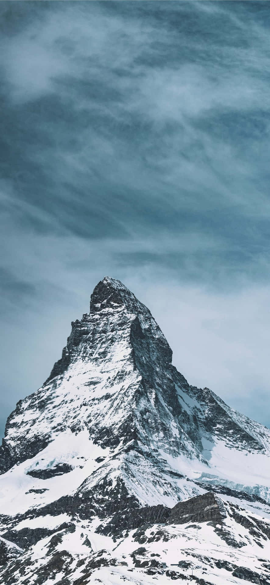 白雪覆蓋的山峰穿過戲劇性的灰色雲層升起。