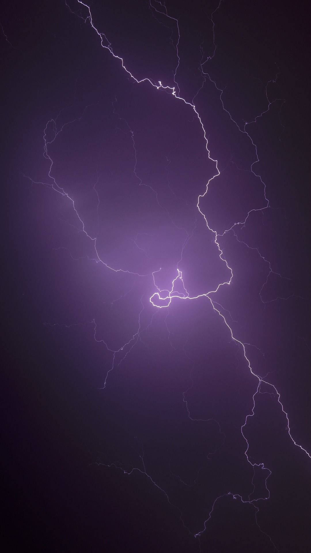 一道鮮豔的紫色閃電照亮了黑暗的暴風雨天空。