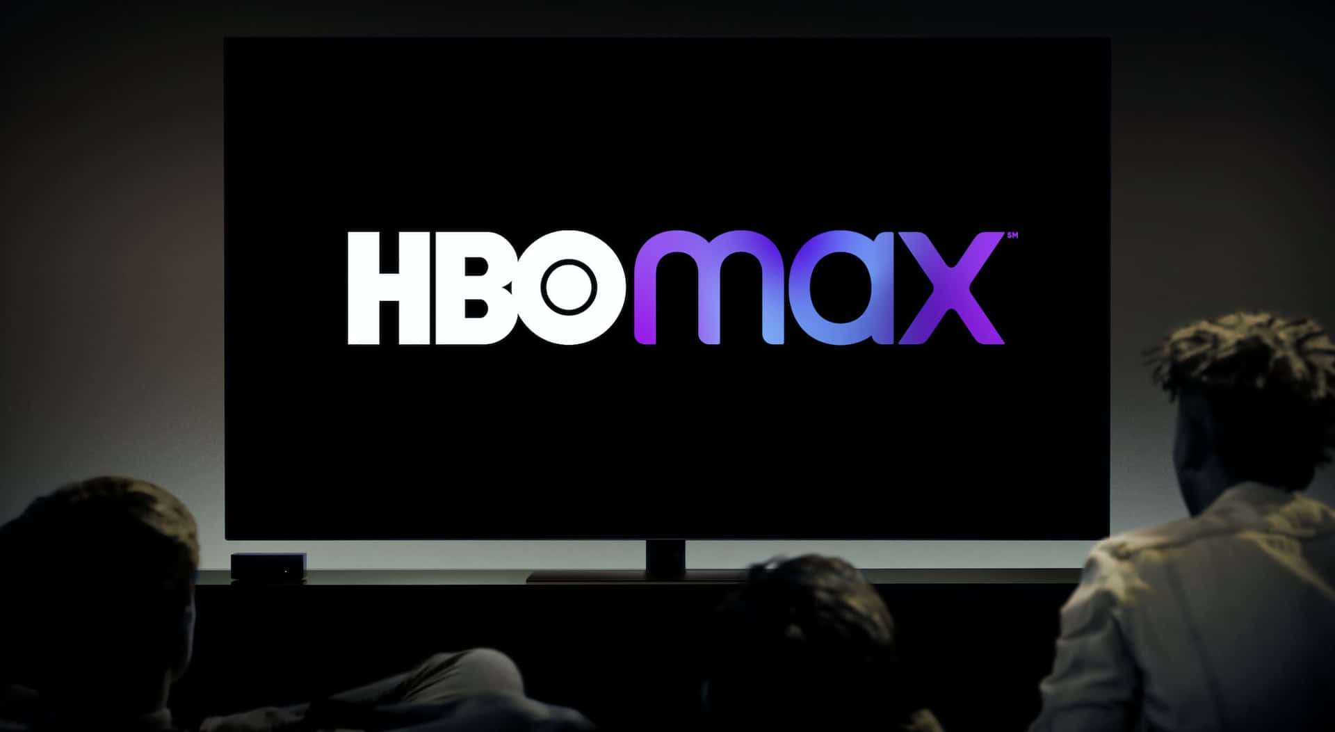 人們在黑暗的影院中觀看大屏幕上的HBO Max標誌。