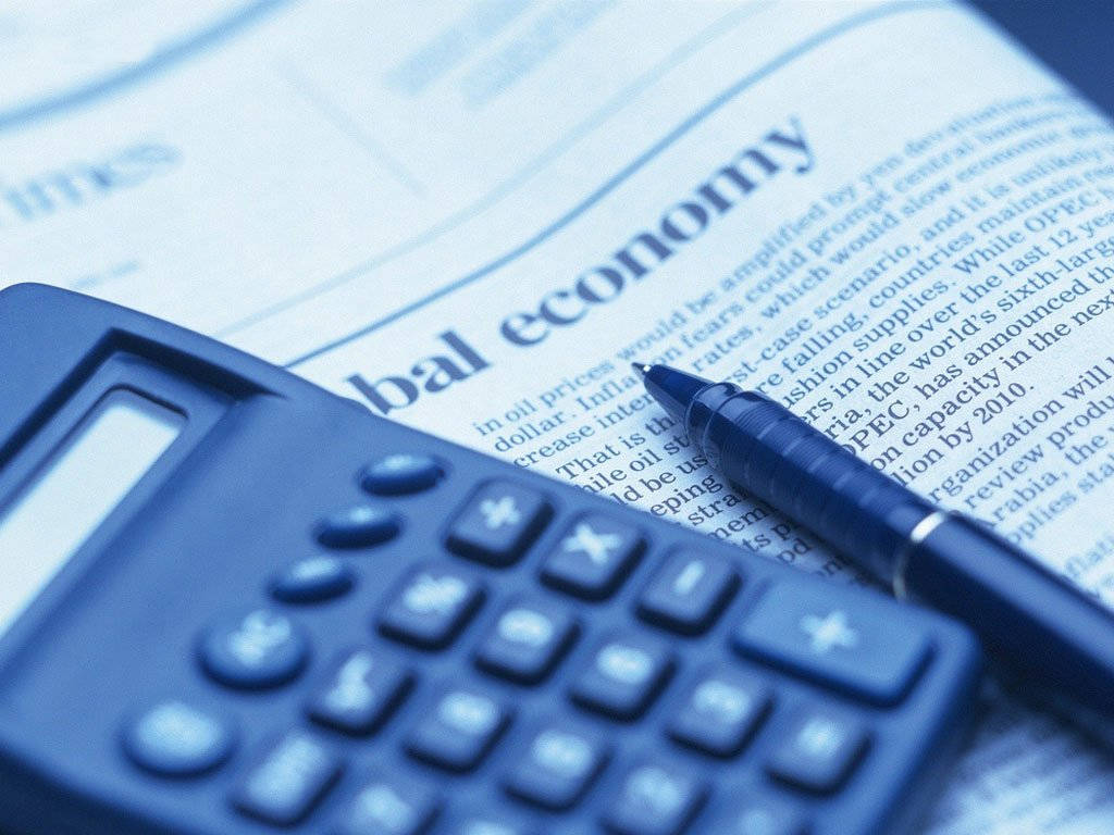 計算器置於報紙上 壁紙 — 一個藍色計算機和一支筆放在一篇關於全球經濟的報紙文章上，處於冷色調單色燈光下。