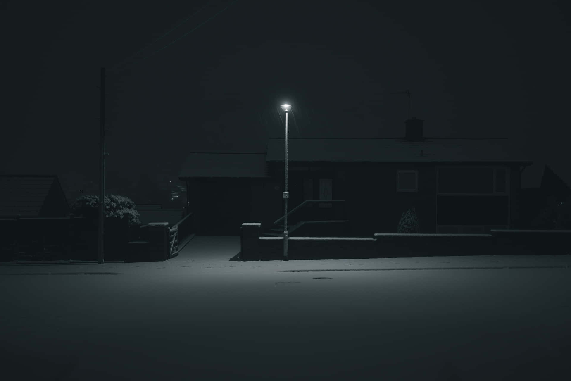 一盞孤獨的路燈在夜晚照亮了積雪的郊區街道。
