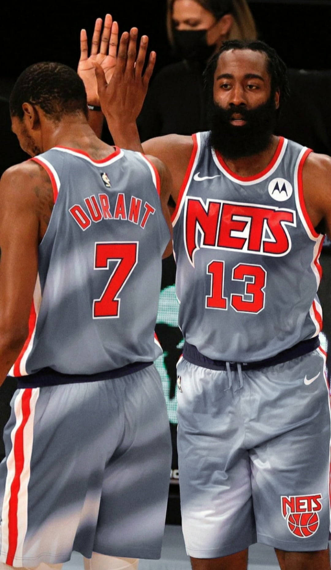 兩名身穿Nets球衣的籃球運動員在球場上擊掌。
