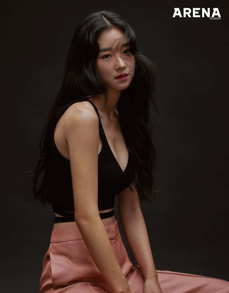 身穿黑色上衣和粉紅色褲子的女性在攝影棚擺姿勢