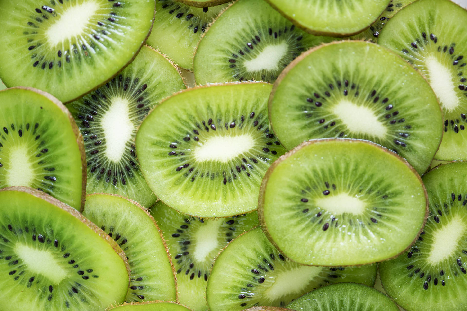 新鮮切片奇異果，顯示綠色果肉和黑色種子。