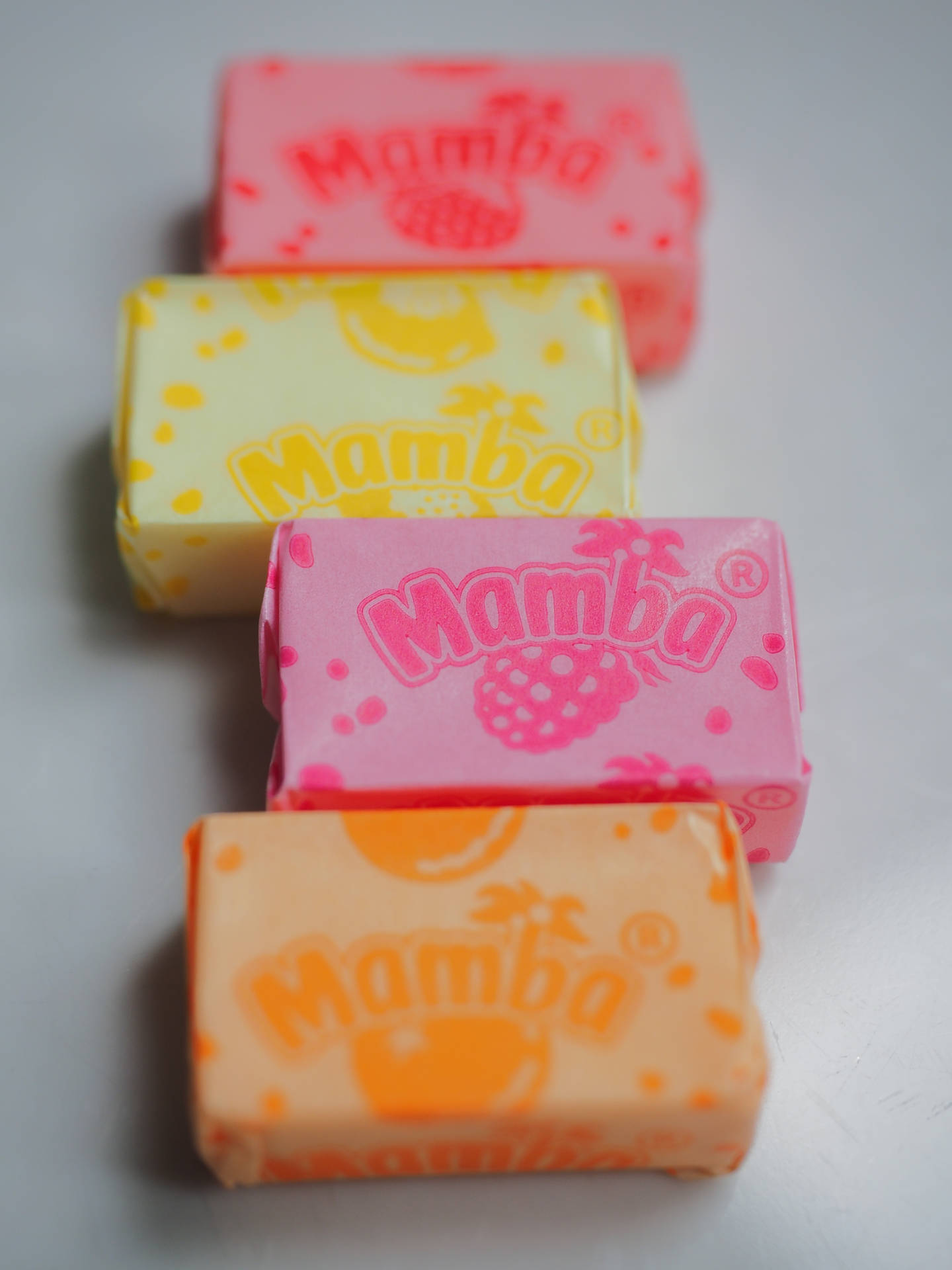 四條Mamba糖果棒以色彩繽紛的包裝對角線排列在白色表面上。