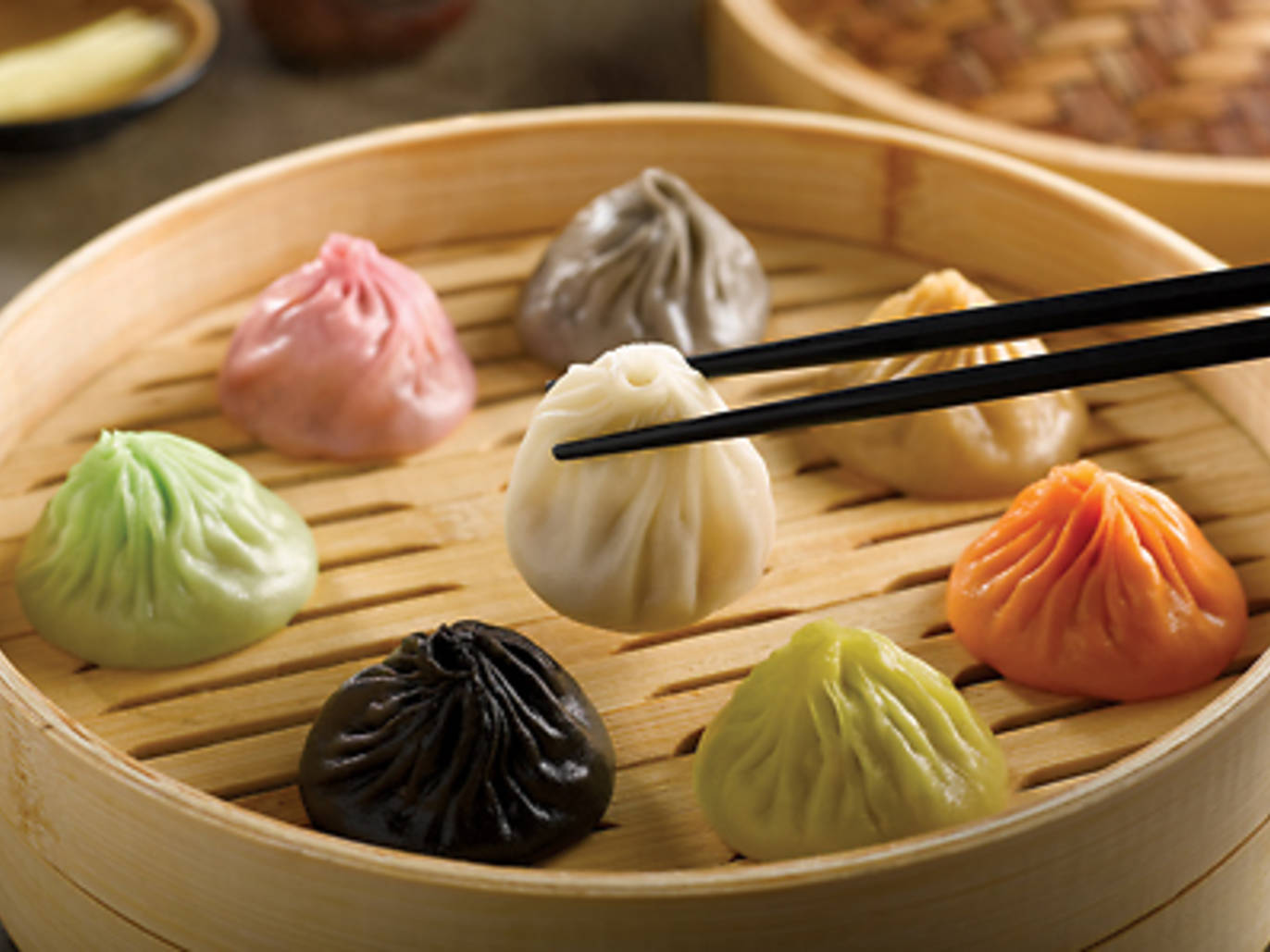 竹籠中的蒸餃，筷子夾起一個餃子。