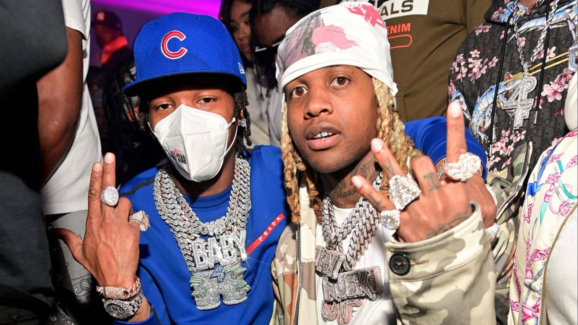 說唱歌手 Lil Durk 與 Lil Baby 壁紙 — 兩位饒舌歌手戴著閃亮珠寶和穿著大膽服裝，在燈光璀璨、人群擁擠的派對上自信擺姿勢。