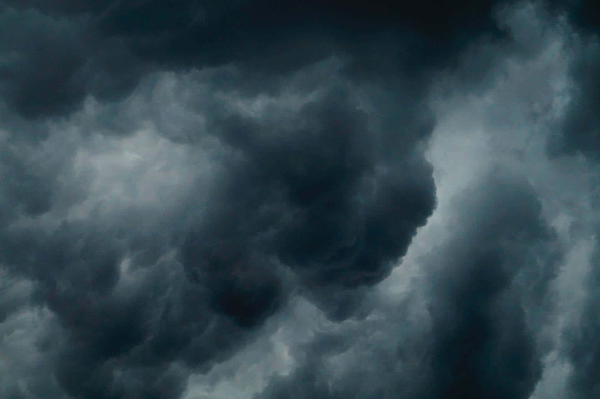 誰說暴風雨一定要悶悶不樂？ 壁紙 — 濃密的黑暗風暴雲在陰沉天空中翻騰，帶有陰暗的灰色和黑色色調。