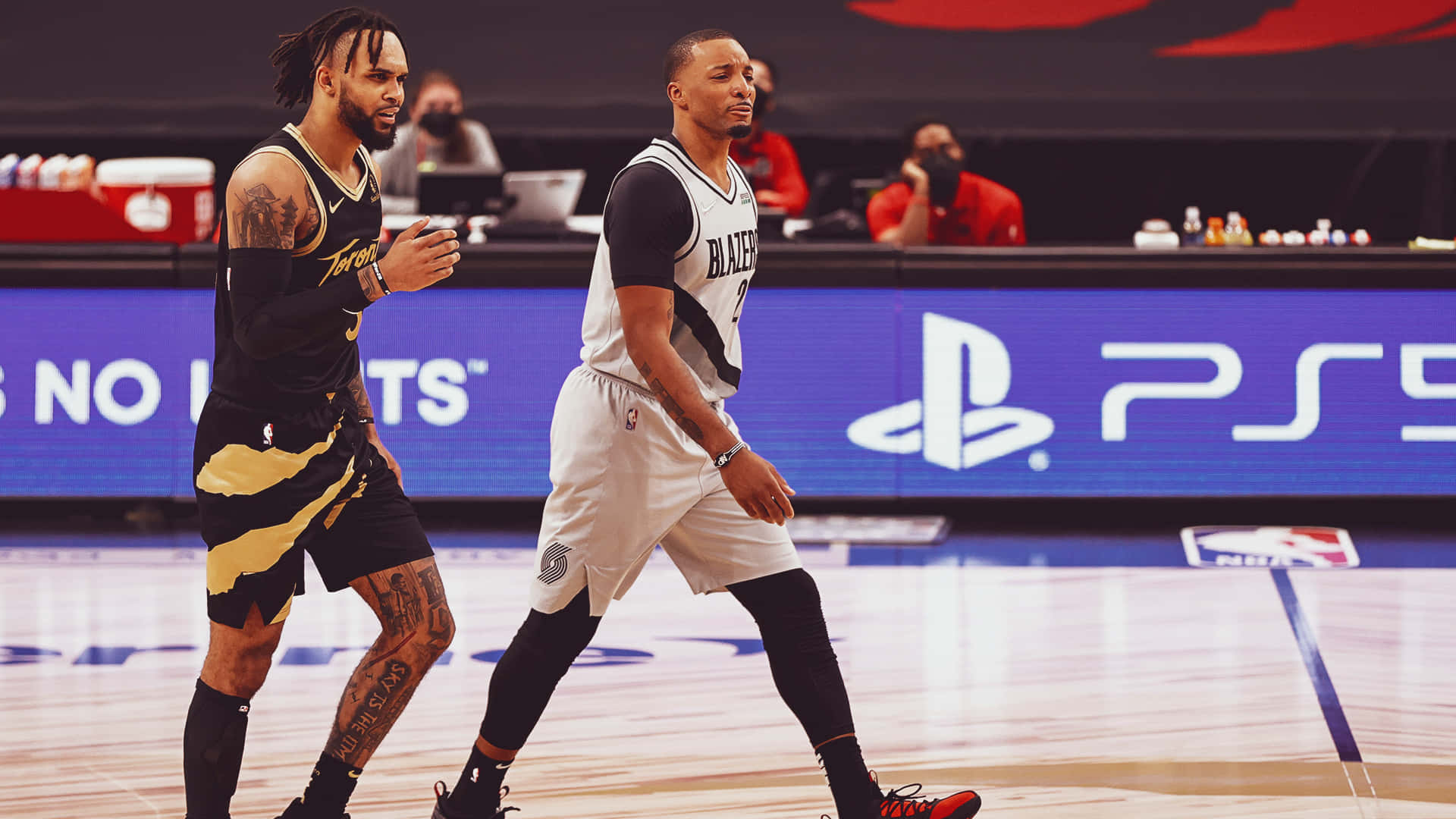 兩位NBA籃球運動員在球場上行走，背景有PS5品牌標誌。