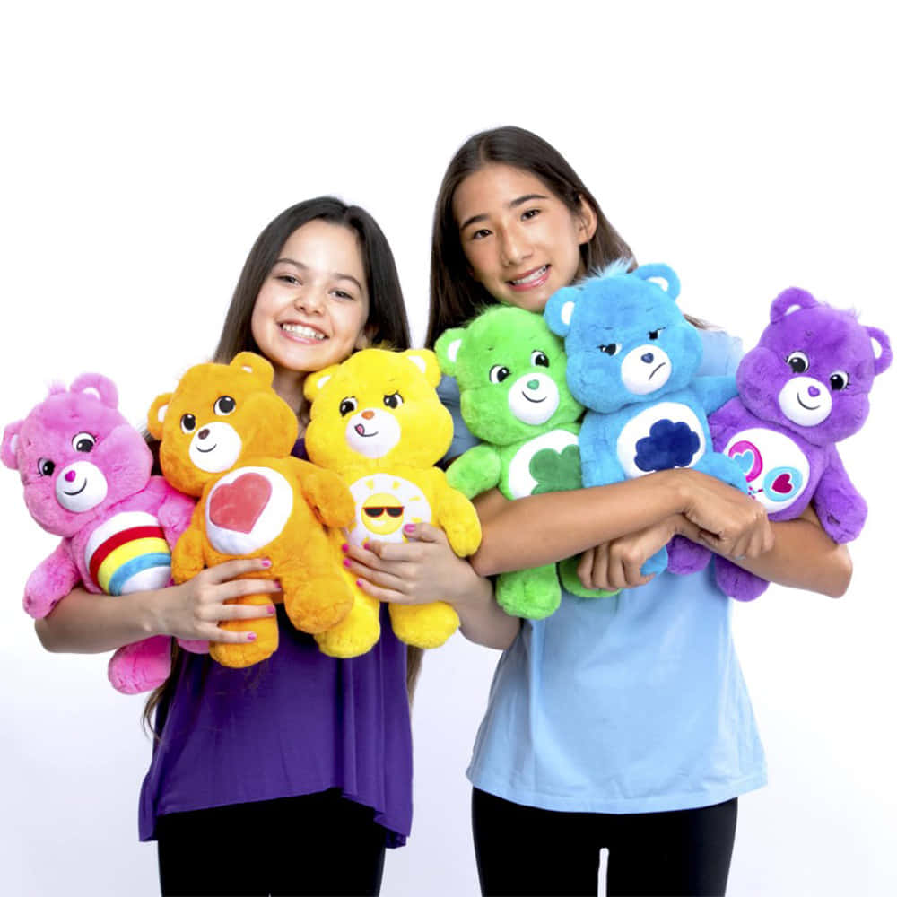 兩個女孩拿著色彩繽紛的Care Bears毛絨玩具，笑容燦爛。