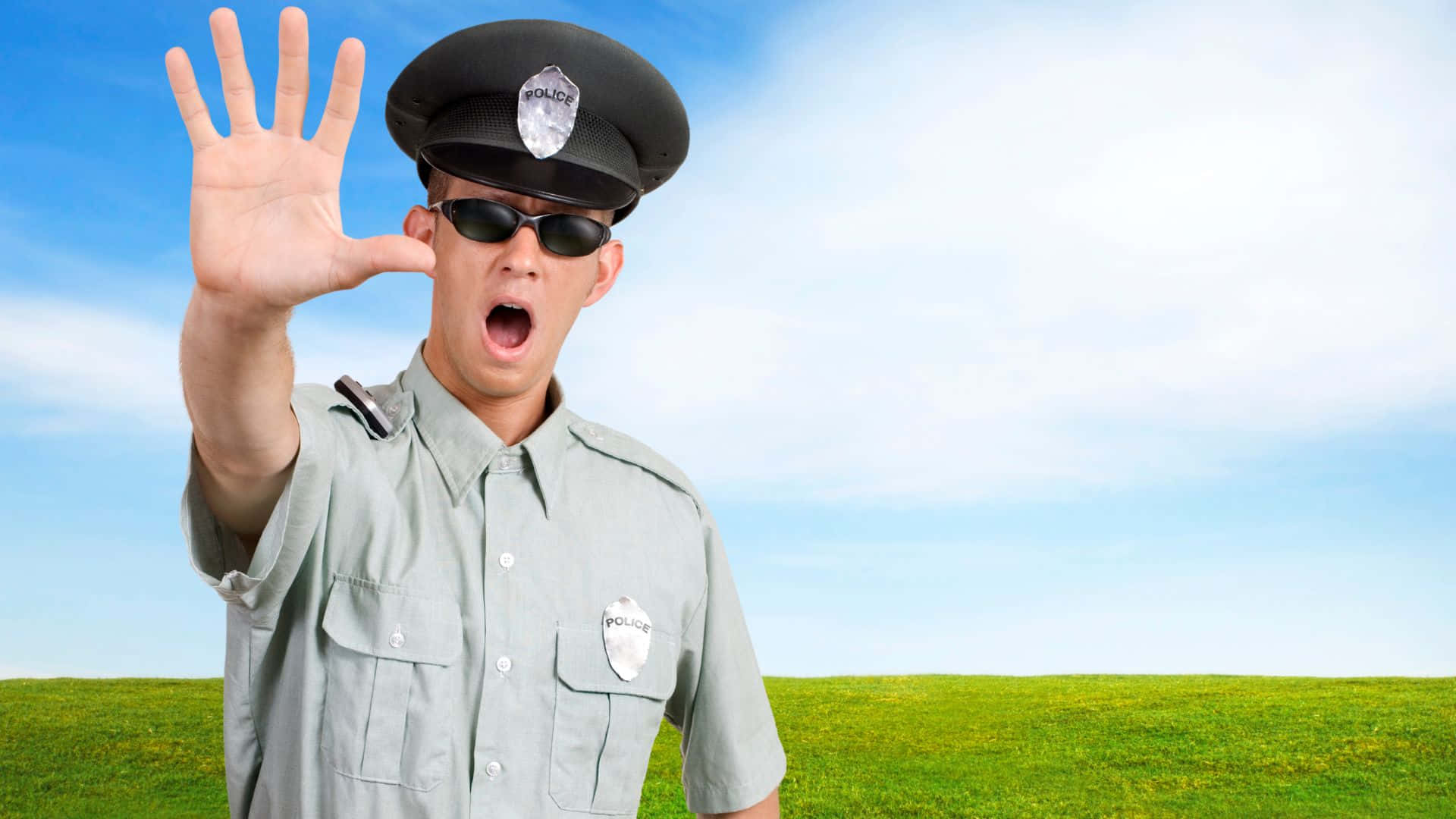 身穿制服的警察喺草地上舉手截停交通。