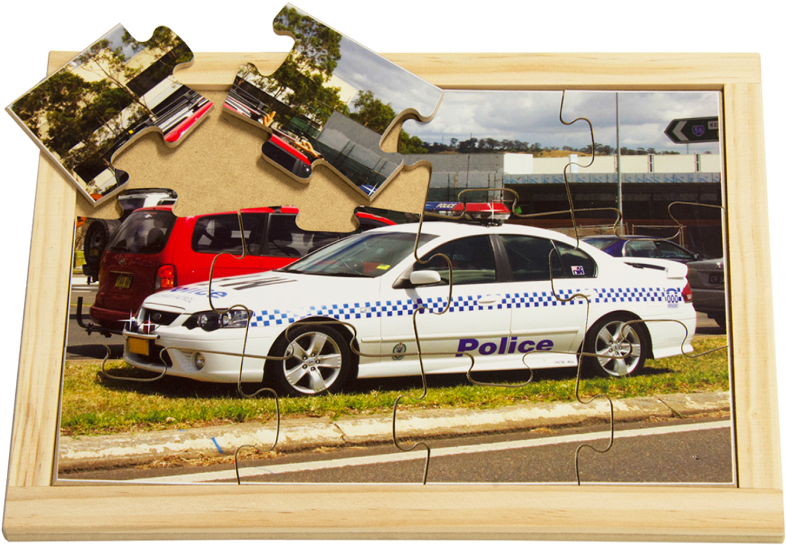 警車拼圖組裝 壁紙 — 一個部分組裝的木框拼圖描繪了一輛白色警車停在草地路邊，背景有其他車輛和樹木。