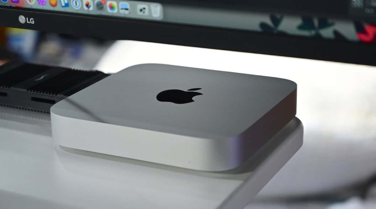 銀色 Apple Mac mini 電腦放在白色桌子上，靠近顯示器。