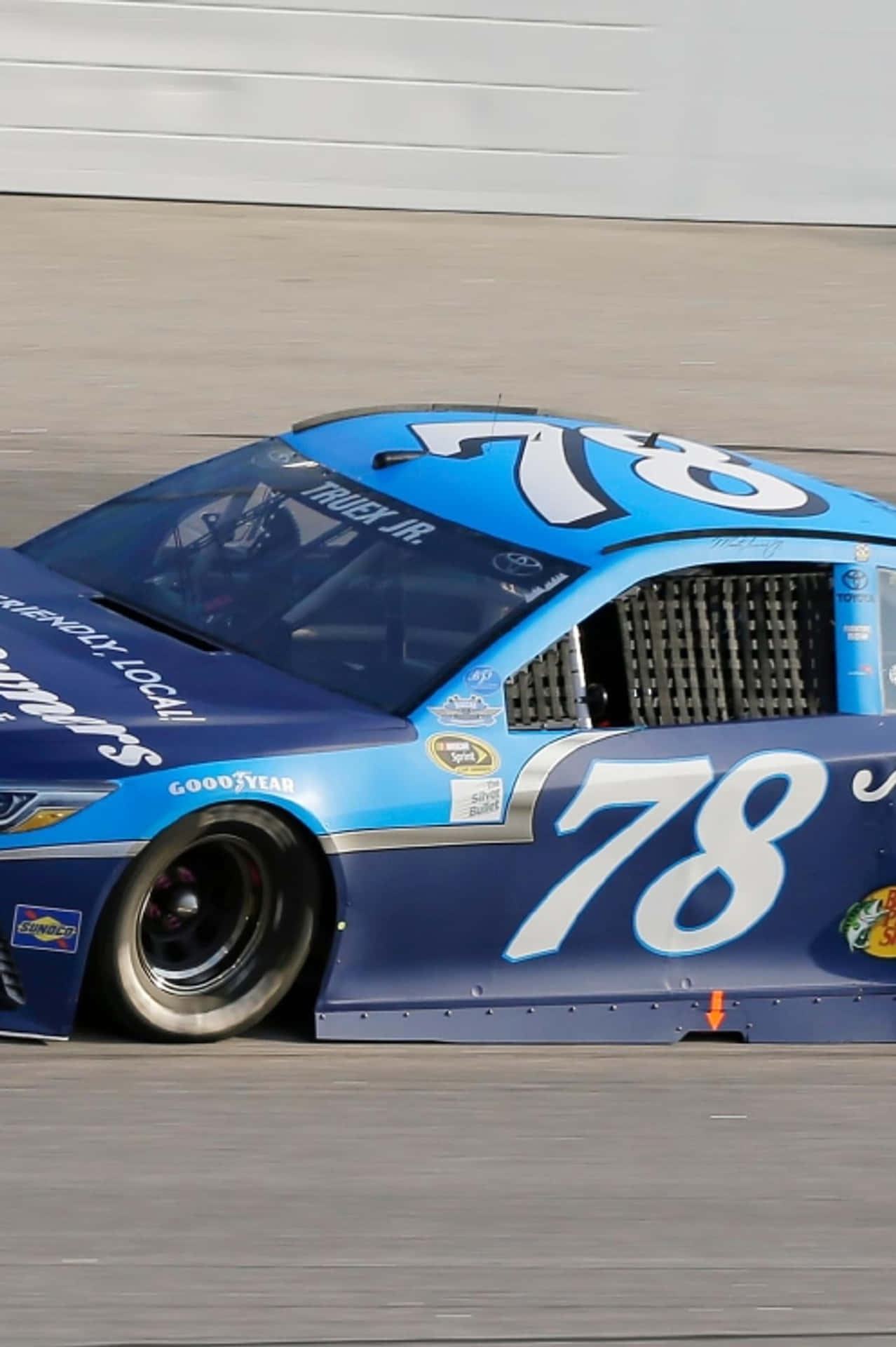藍白相間的 NASCAR 卡車在賽道上奔馳，帶有動態模糊。