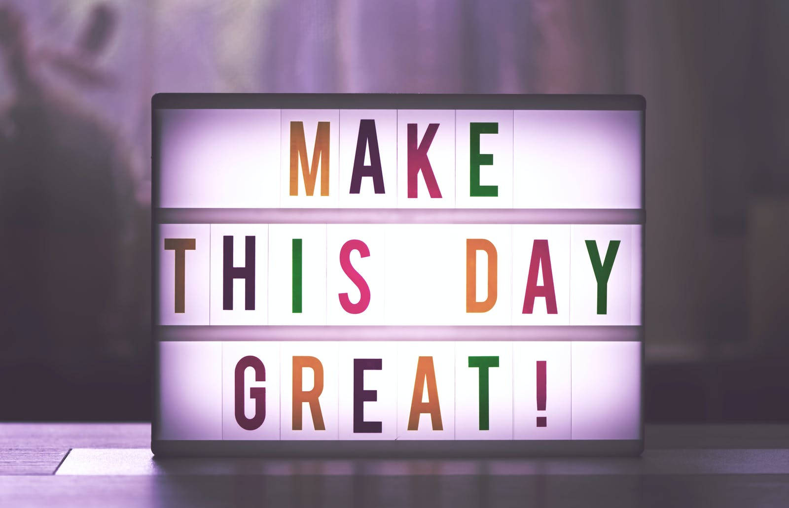 讓今天偉大勵志語錄 壁紙 — 一個明亮照明的標誌，用彩色字母拼出「MAKE THIS DAY GREAT!」，背景柔和模糊。