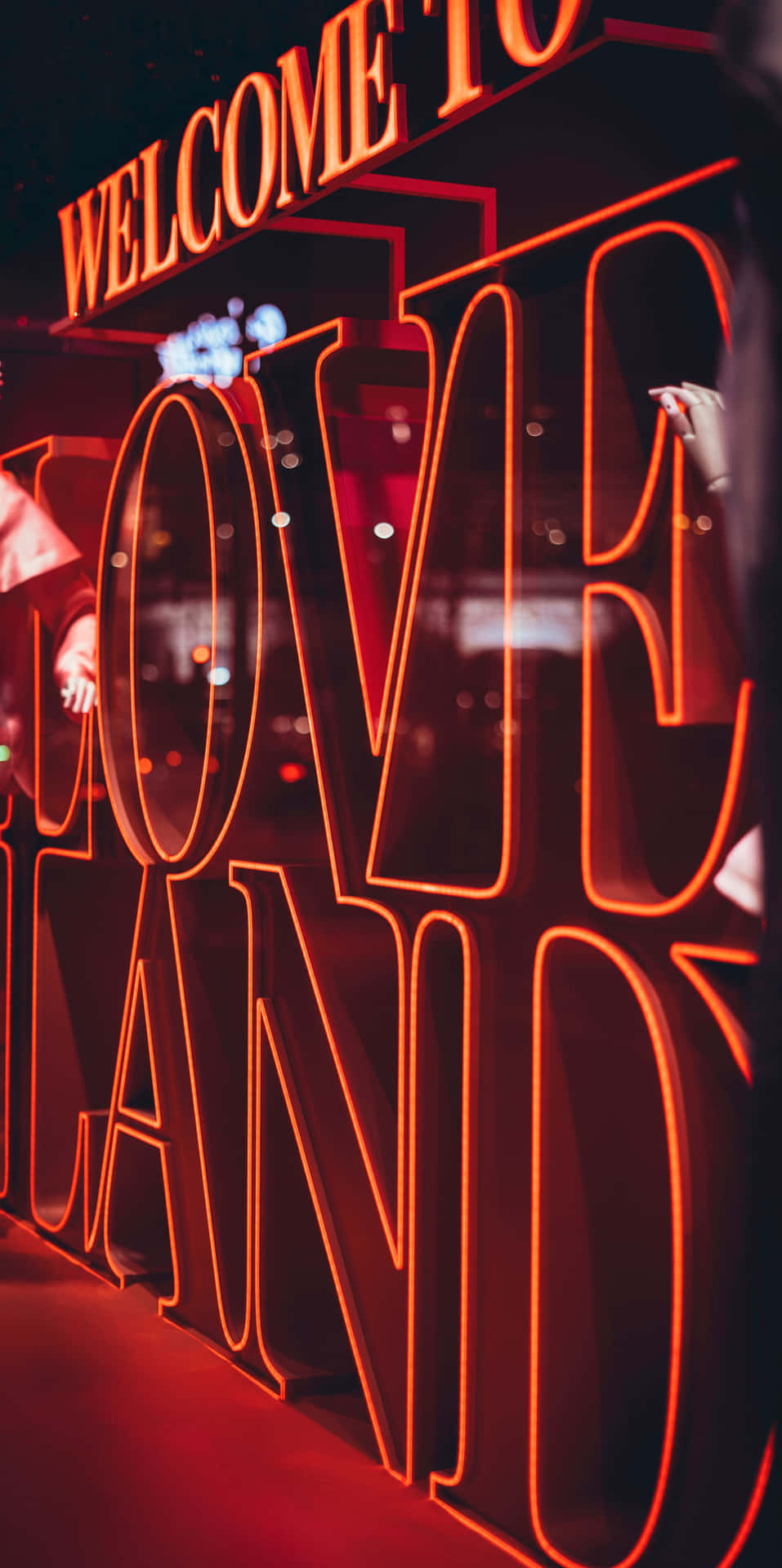 在昏暗空間中發出紅光的霓虹燈牌，上面寫著「welcome to love land」。