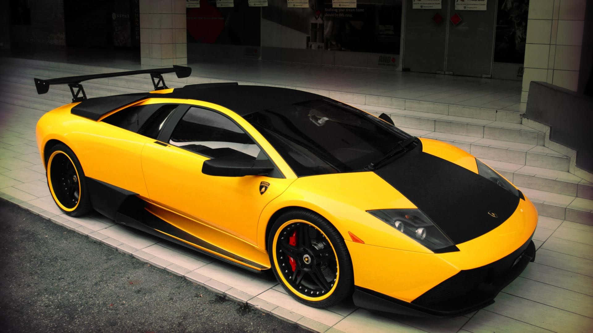 黃黑色林寶堅尼 Murciélago 停泊在建築物附近的行人路上。