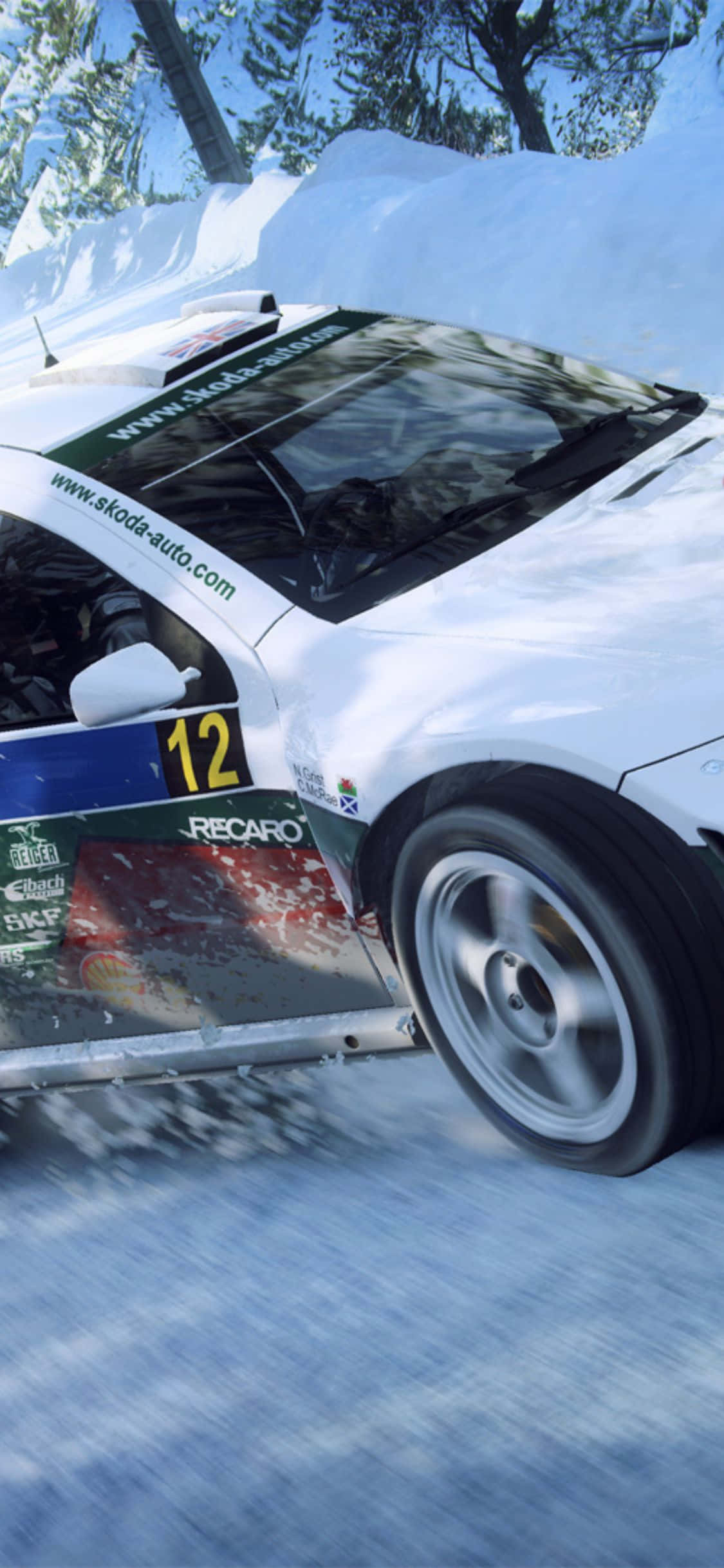 讓天空成為你的極限，在《Dirt Rally》中飛躍 壁紙 — 一輛白色拉力賽車，編號12，在雪地森林賽道上飛馳，揚起雪霧。