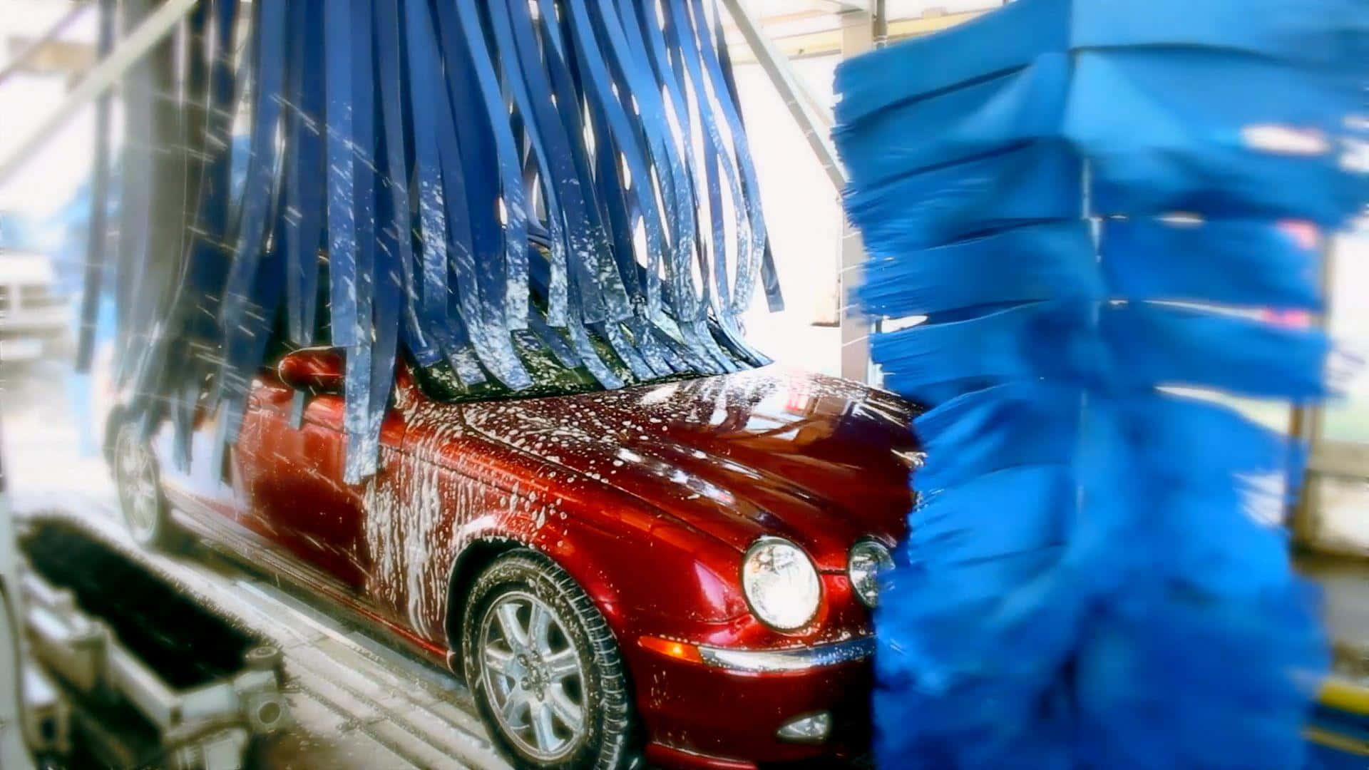 紅色汽車在自動洗車機中被藍色刷子清潔。