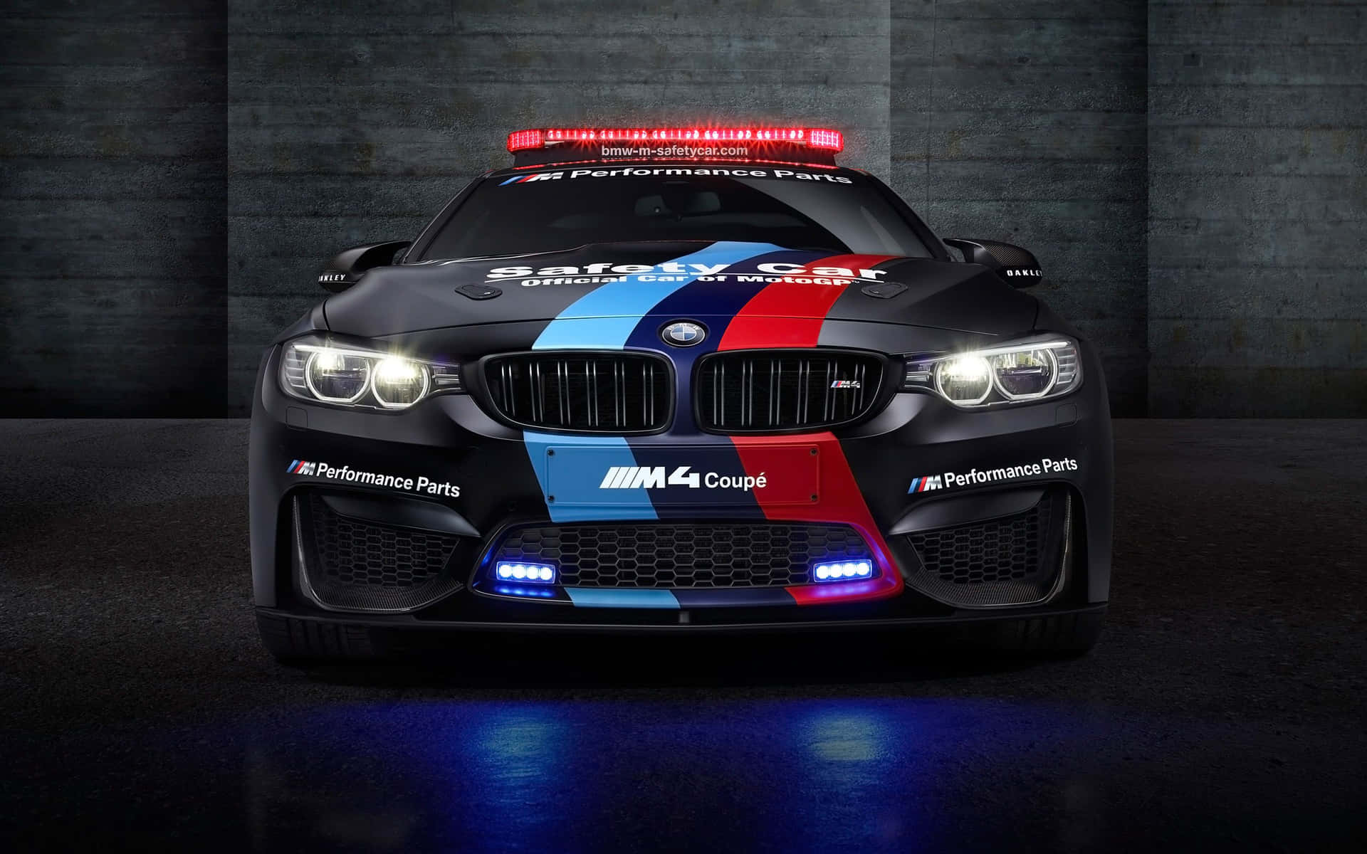 黑色BMW M4 Coupe安全車，帶有紅藍條紋和閃爍燈光，在黑暗車庫中。