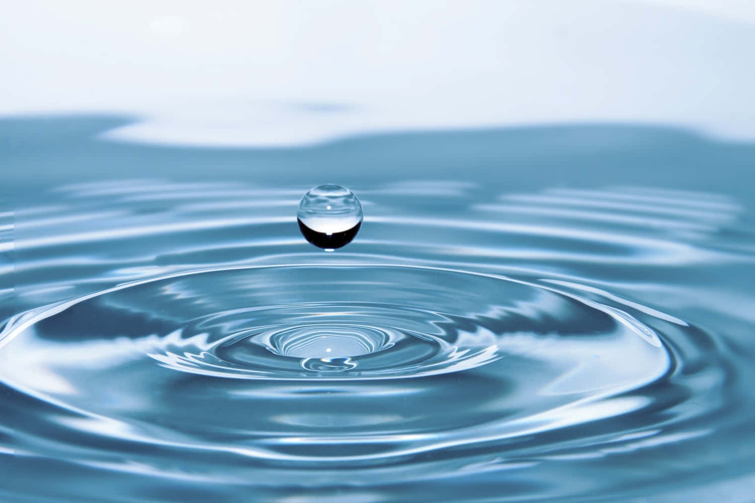 懸浮的水滴在平靜的藍色水面上產生漣漪。