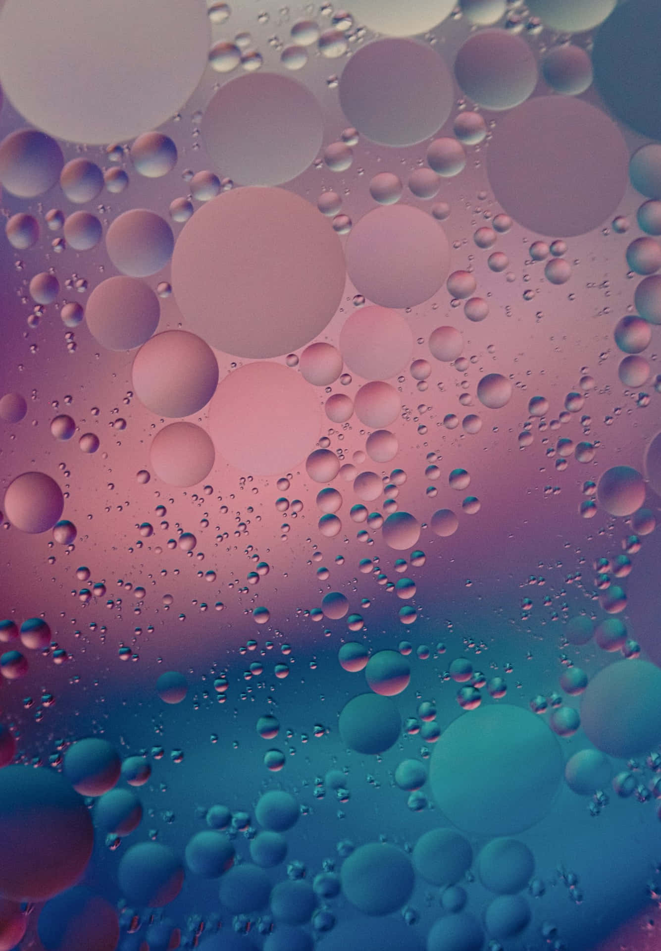 粉紅與青綠色漸變的浮油泡泡抽象圖案。