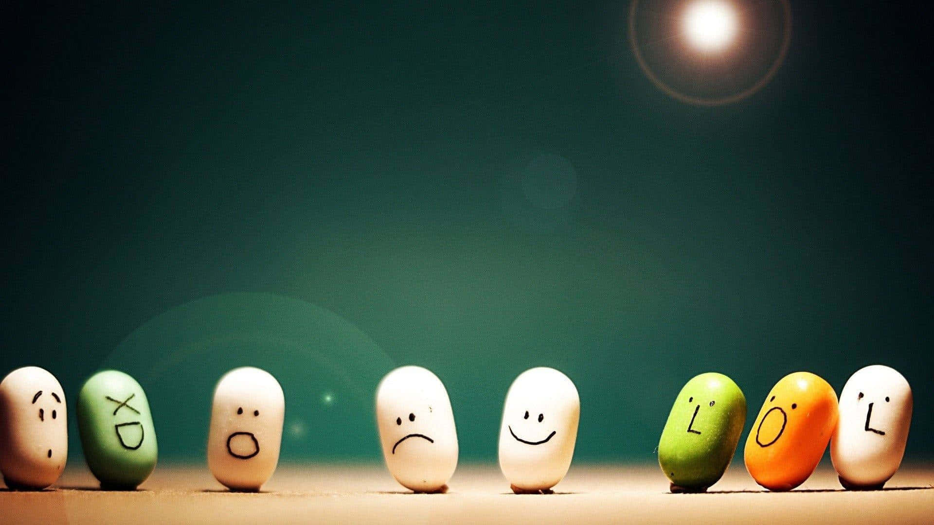 讓笑容綻放在你的臉上 壁紙 — 一排塗漆的石頭，在柔和的聚光燈下，帶有表情豐富的臉孔，背景為深綠色。