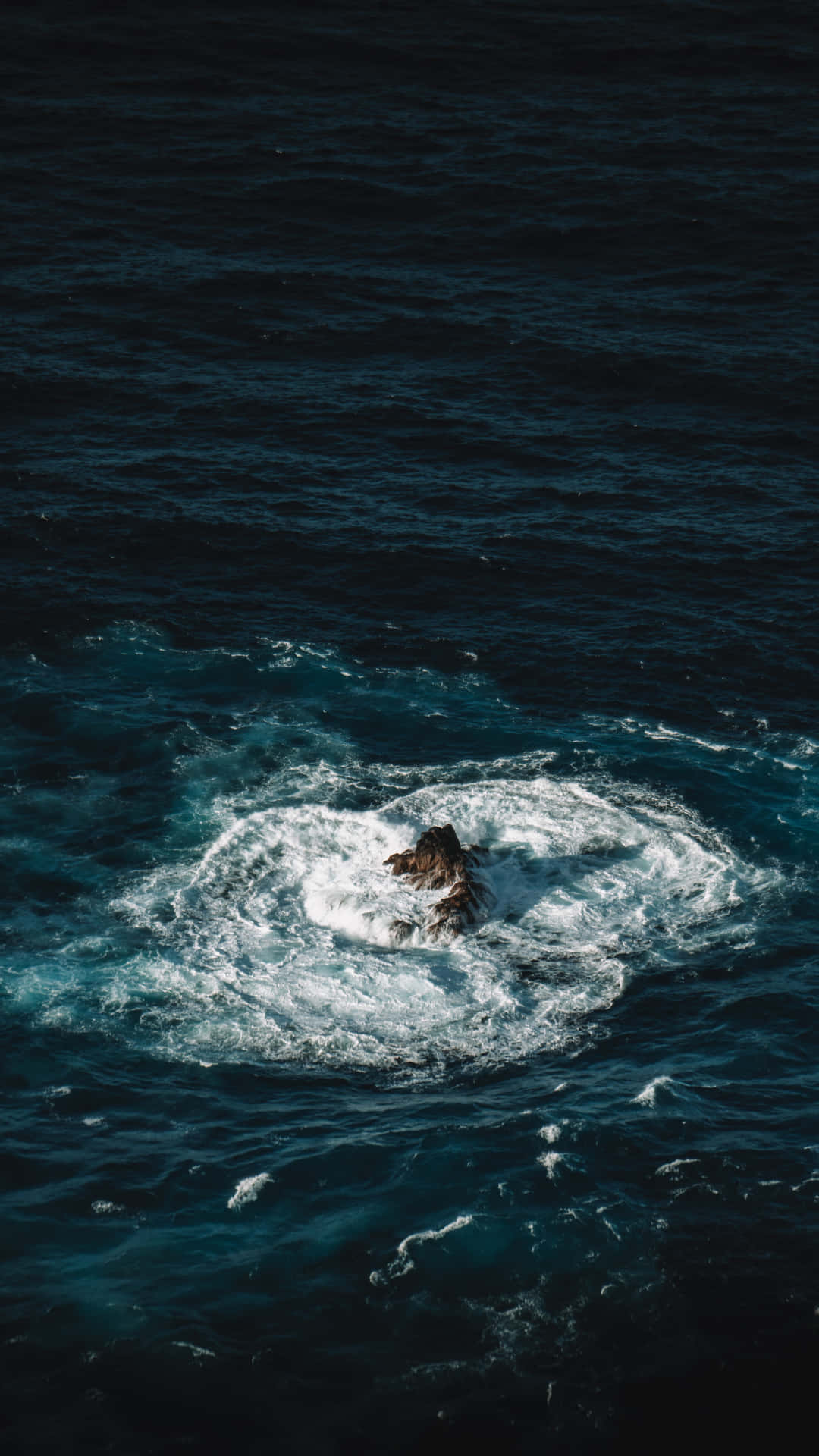 海洋中的孤獨岩石，當海浪拍打周圍時產生白色泡沫。