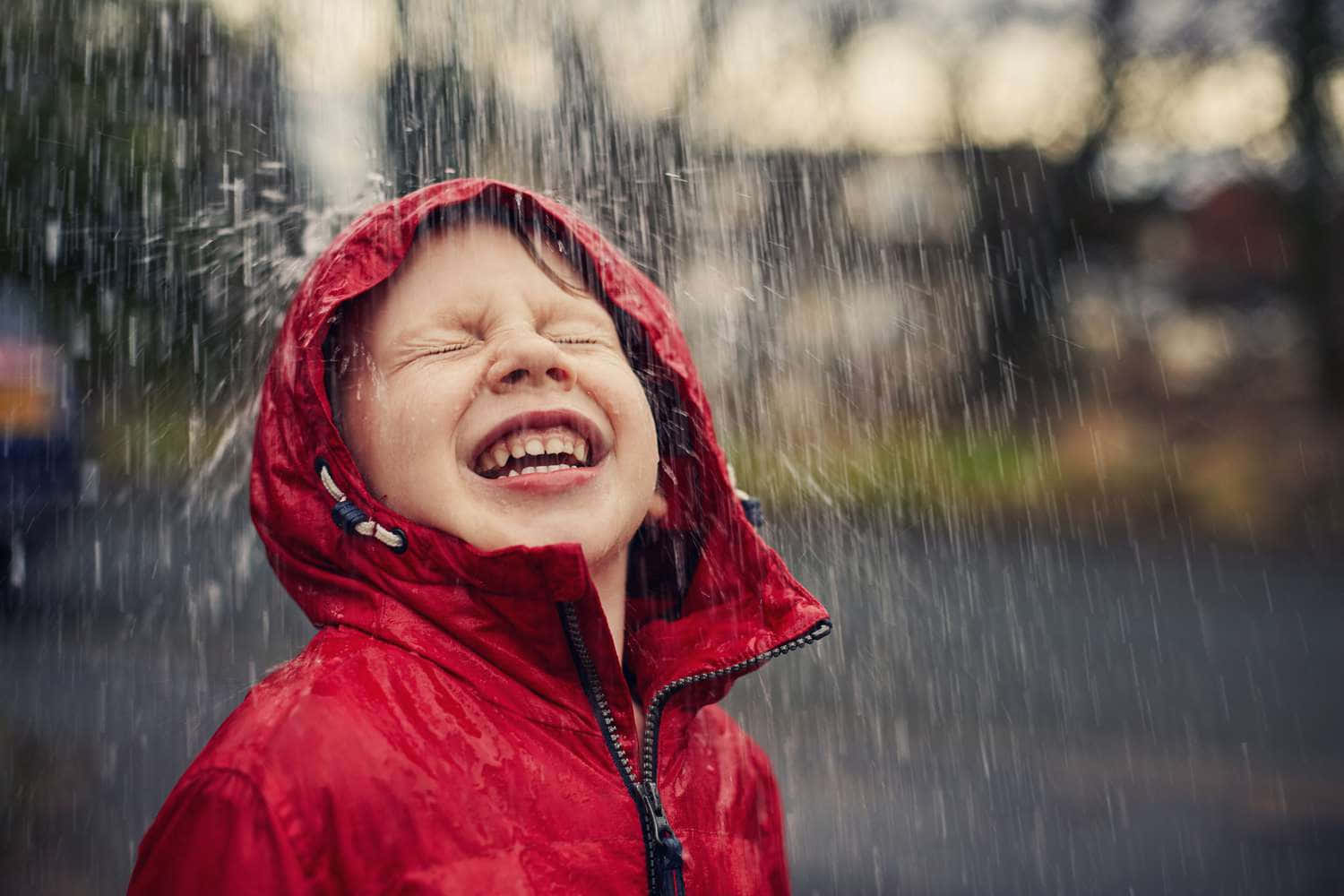 孩子穿著紅色連帽外套在雨中大笑