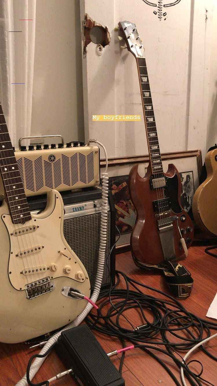 讓音樂自己說話 壁紙 — 復古電結他和擴音器散落在木地板上，電線纏繞，後面牆上有個洞。