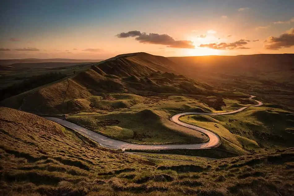 夕陽下蜿蜒穿過起伏綠色山丘的道路