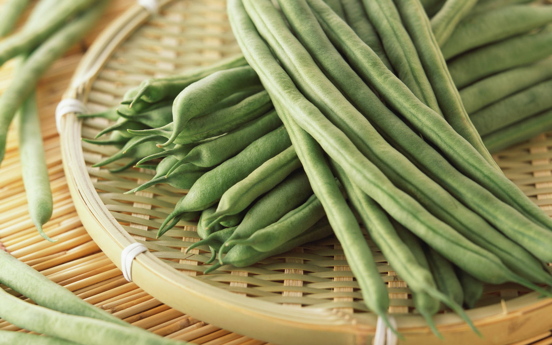 豆角蔬菜 壁紙 — 新鮮青豆堆疊在編織竹籃中，自然光突顯其鮮豔色彩和質感。