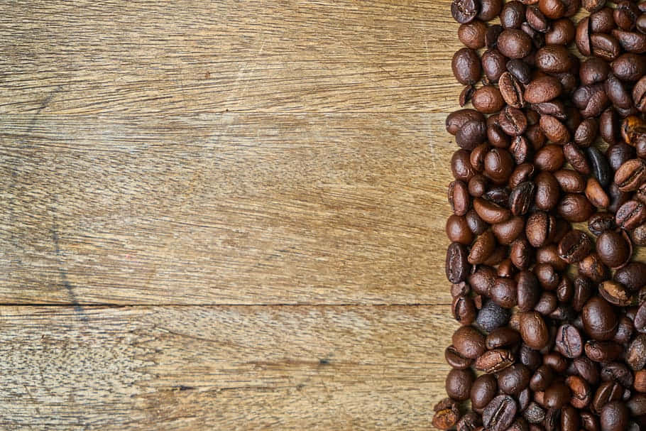 Brown Coffee 桌布 壁紙 — 豐富的烘焙咖啡豆散落在風化的木質表面上，呈現質樸的俯視構圖。