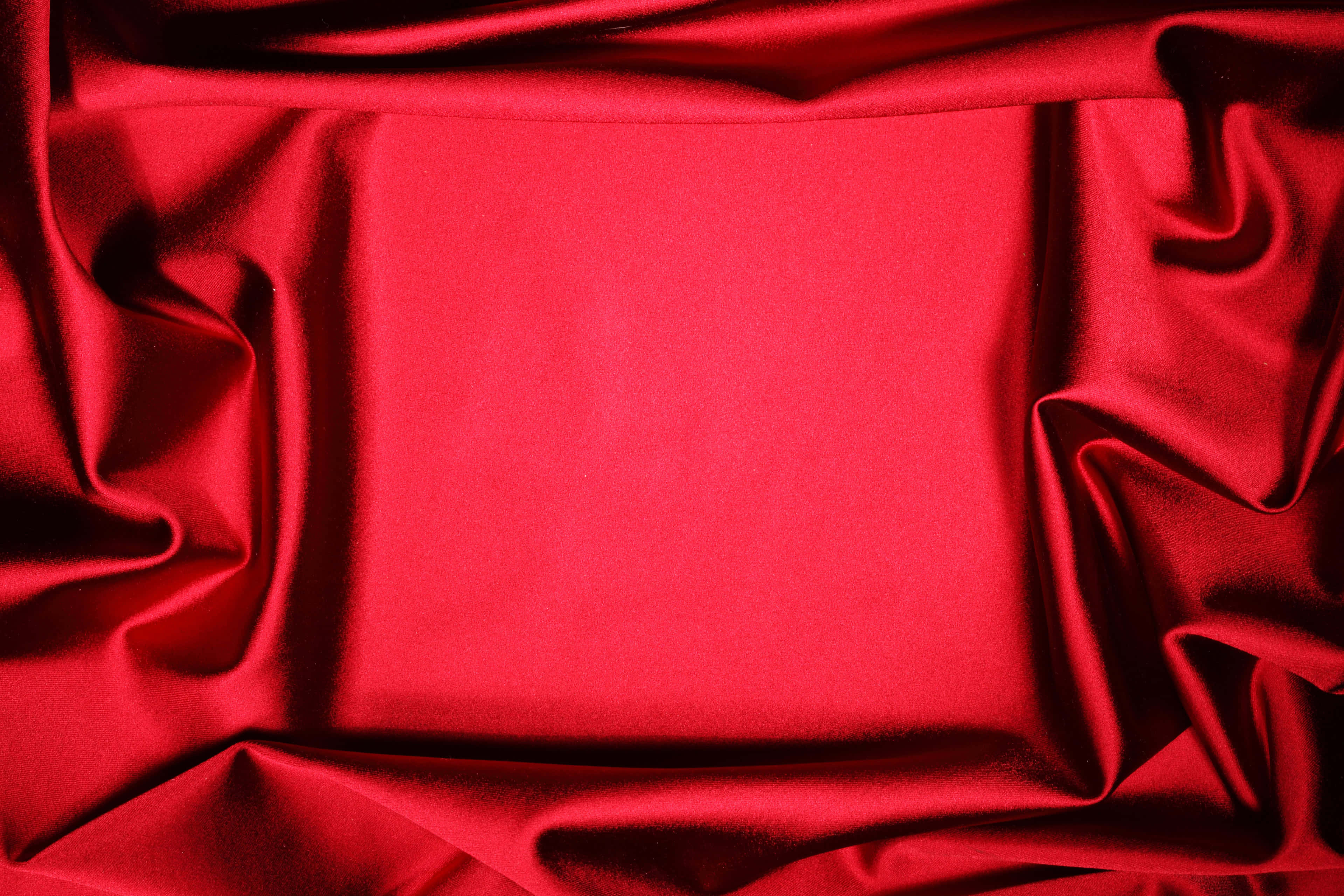 Red Velvet 桌布 壁紙 — 豐富的紅色緞面布料以優雅的褶皺垂墜，營造出帶有柔和亮點和深邃陰影的奢華紋理背景。