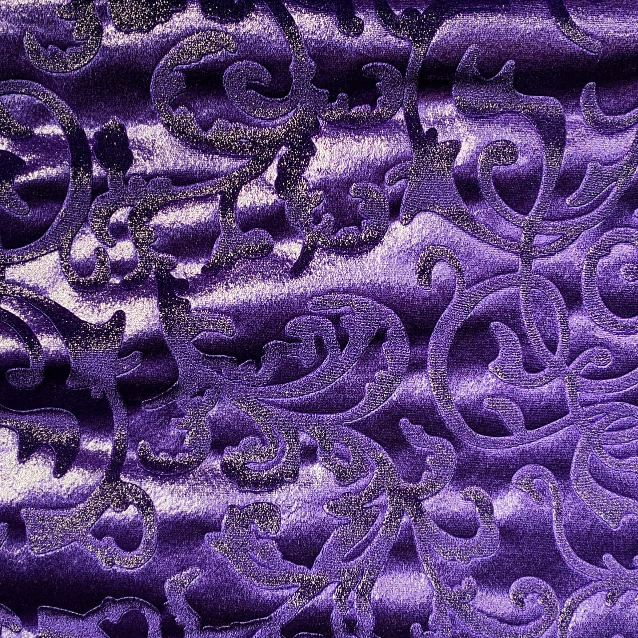 Purple Velvet 桌布 壁紙 — 豐富的紫色天鵝絨布料，帶有閃閃發光的銀色錦緞漩渦和捕捉光線的深褶皺。