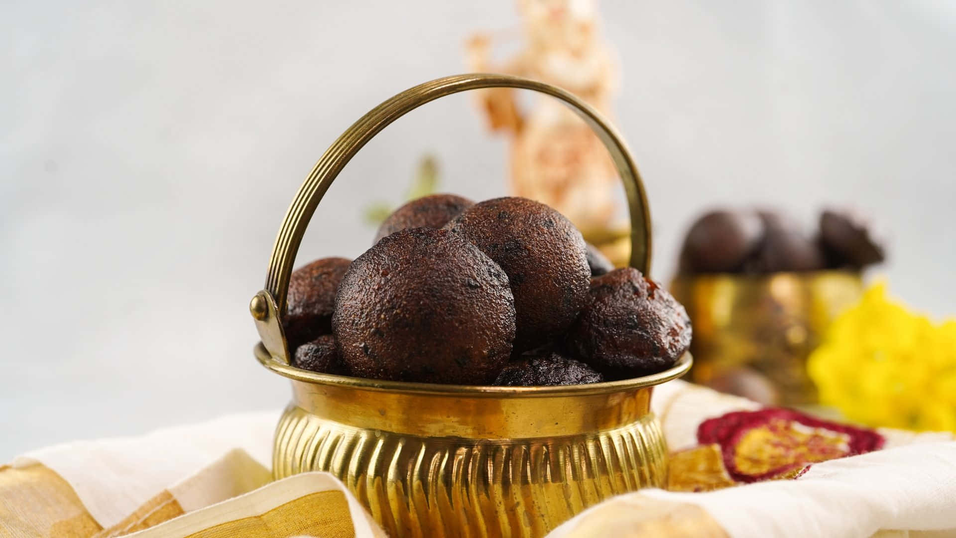 Vishu 桌布 壁紙 — 豐富的黑松露朱古力放在閃亮的黃銅籃子裡，置於帶有花卉圖案的奶油色布上。