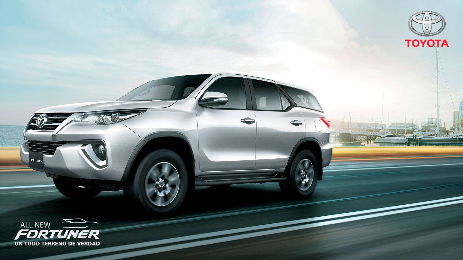 銀色豐田 Fortuner SUV 在碼頭附近的海岸道路上快速行駛。