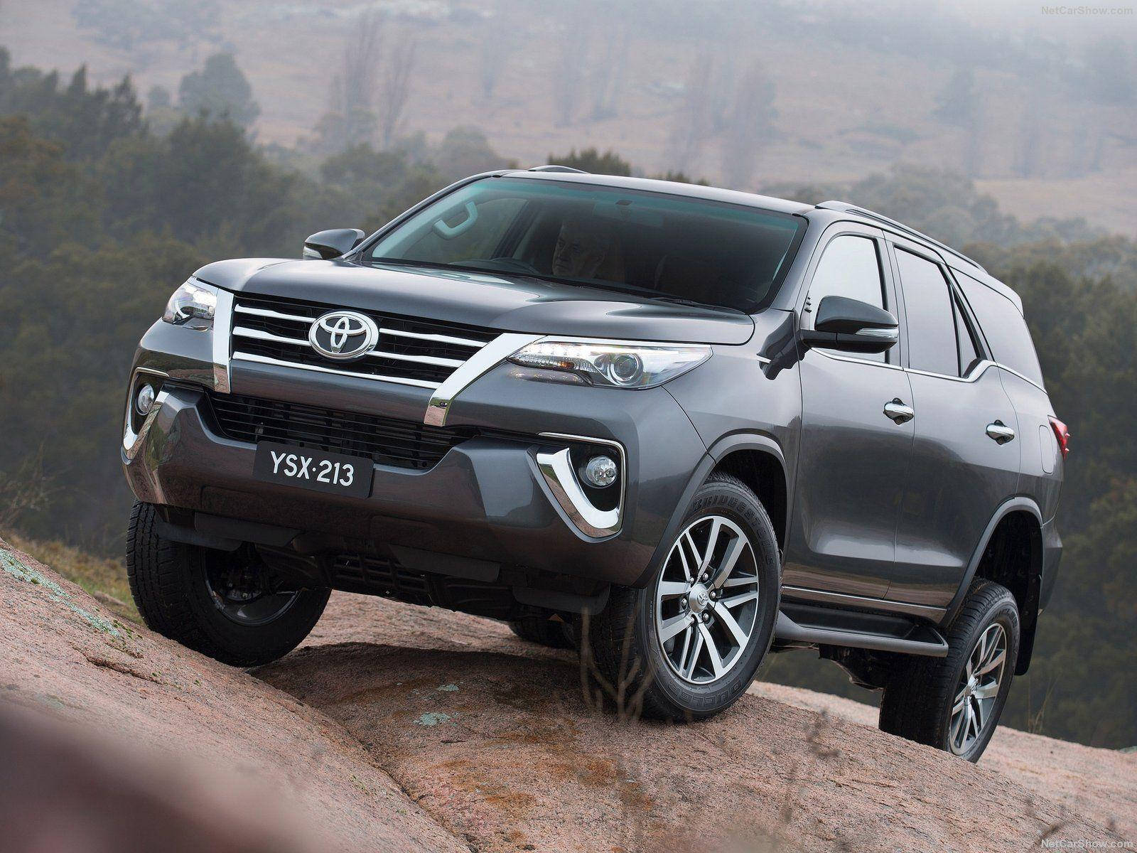 灰色豐田 Fortuner SUV 在森林背景下攀爬岩石山坡
