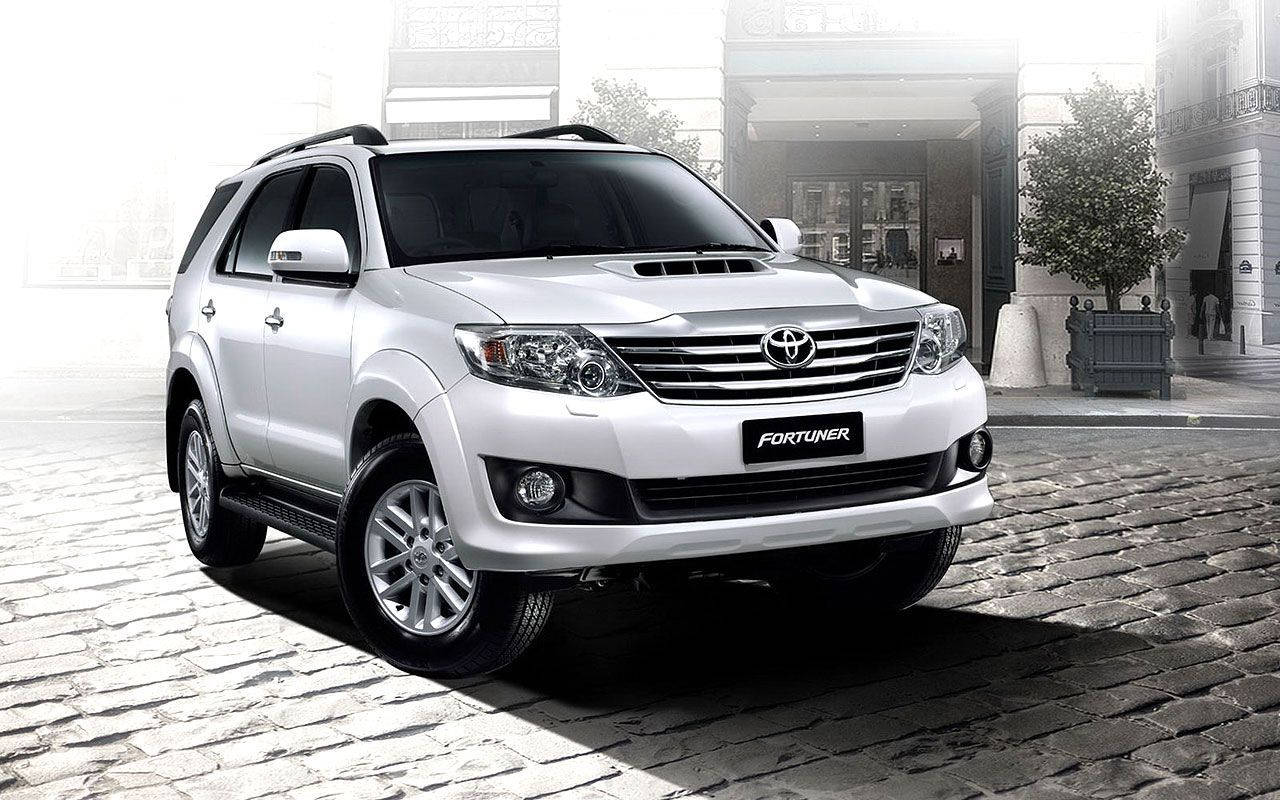 白色豐田 Fortuner SUV 停泊在建築物附近的鵝卵石街道上