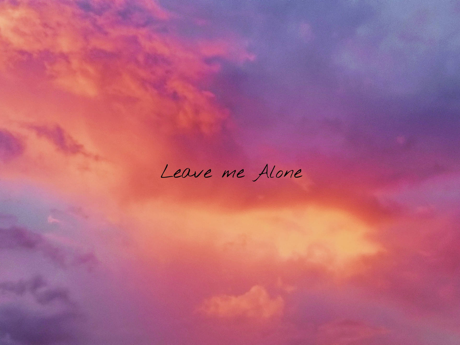 戲劇性的日落天空，帶有粉紅色、紫色和橙色的雲層和手寫文字 leave me alone。