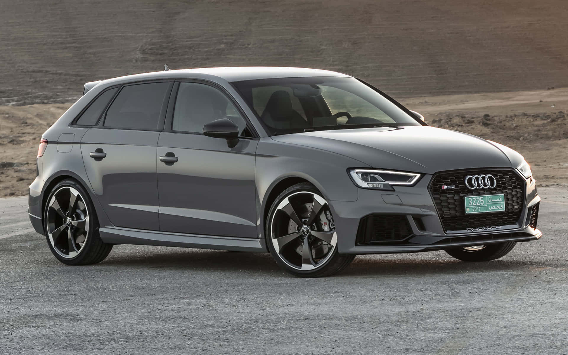 灰色奧迪RS3 Sportback停在沙漠山丘附近的碎石上。