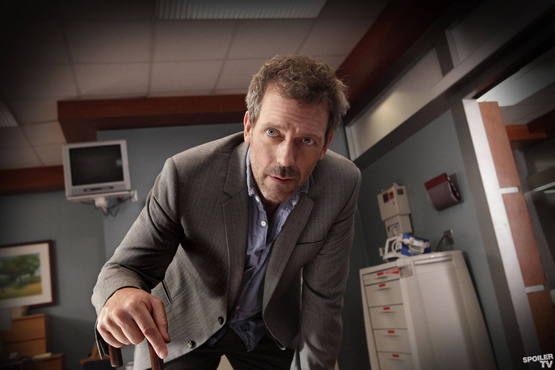 身穿灰色西裝的男子在辦公室中表情激烈地向前傾身
