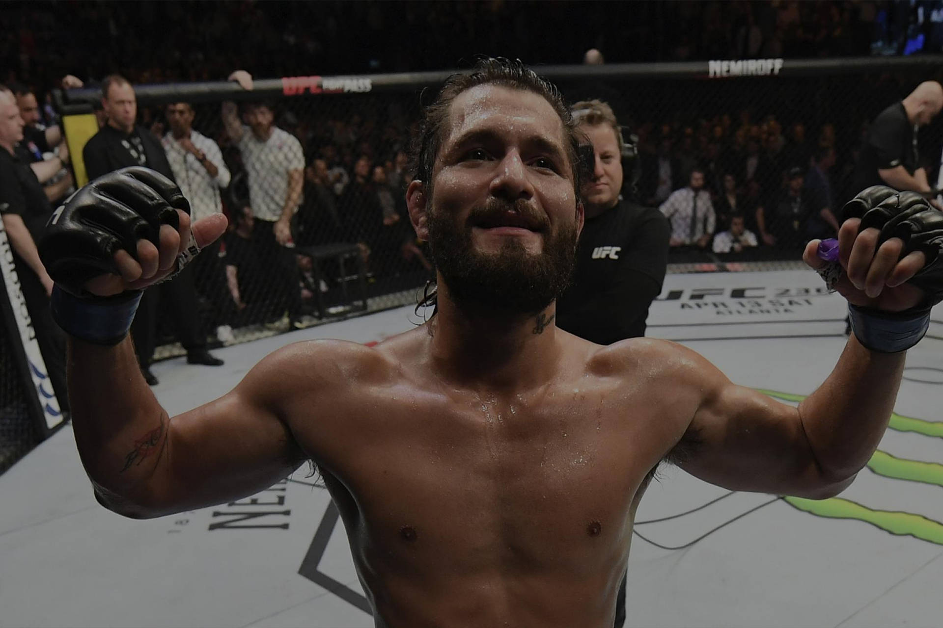 MMA拳手在八角籠中高舉雙臂慶祝勝利。