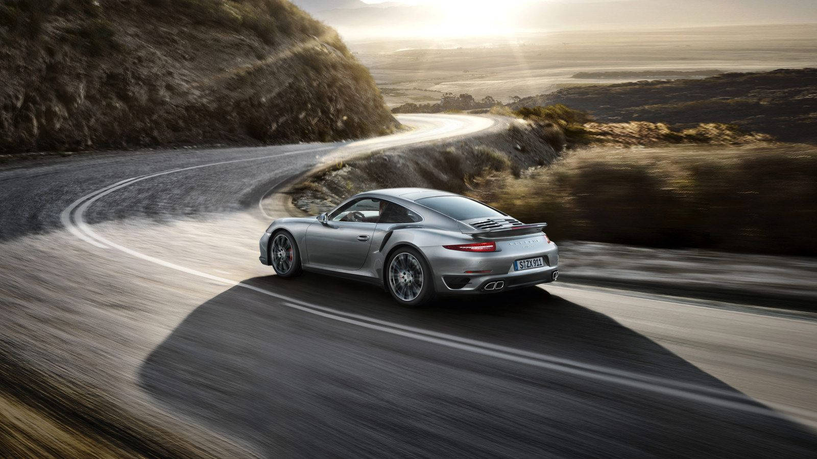 銀色保時捷911 Turbo在日落時分的海岸公路上飛馳。