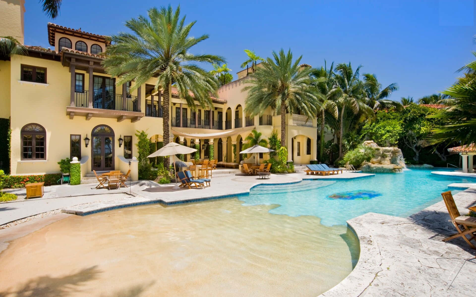Mansion 桌布 壁紙 — 豪華地中海風格別墅，棕櫚樹和閃閃發光的泳池，在明亮的藍天下。