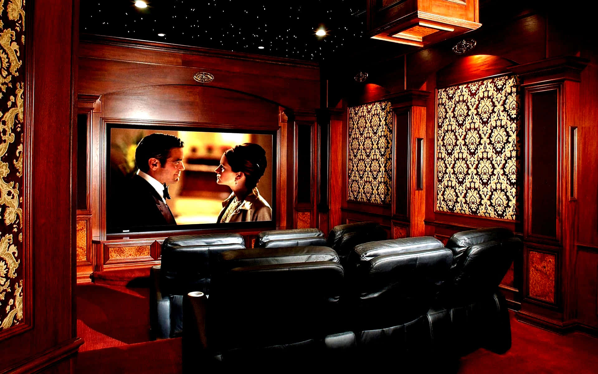 Home Cinema 桌布 壁紙 — 豪華家庭影院，配有豐富的木鑲板、黑色皮革躺椅，以及大屏幕上方的星空天花板，顯示浪漫場景。