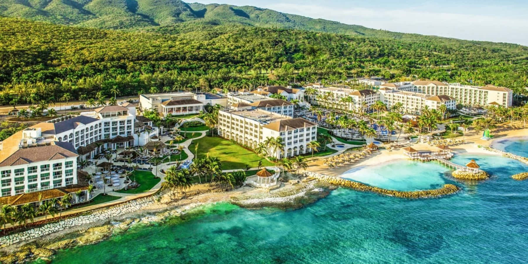 Jamaica 桌布 壁紙 — 豪華度假村坐落在鬱鬱蔥蔥的綠色山脈和碧綠海水之間的鳥瞰圖。
